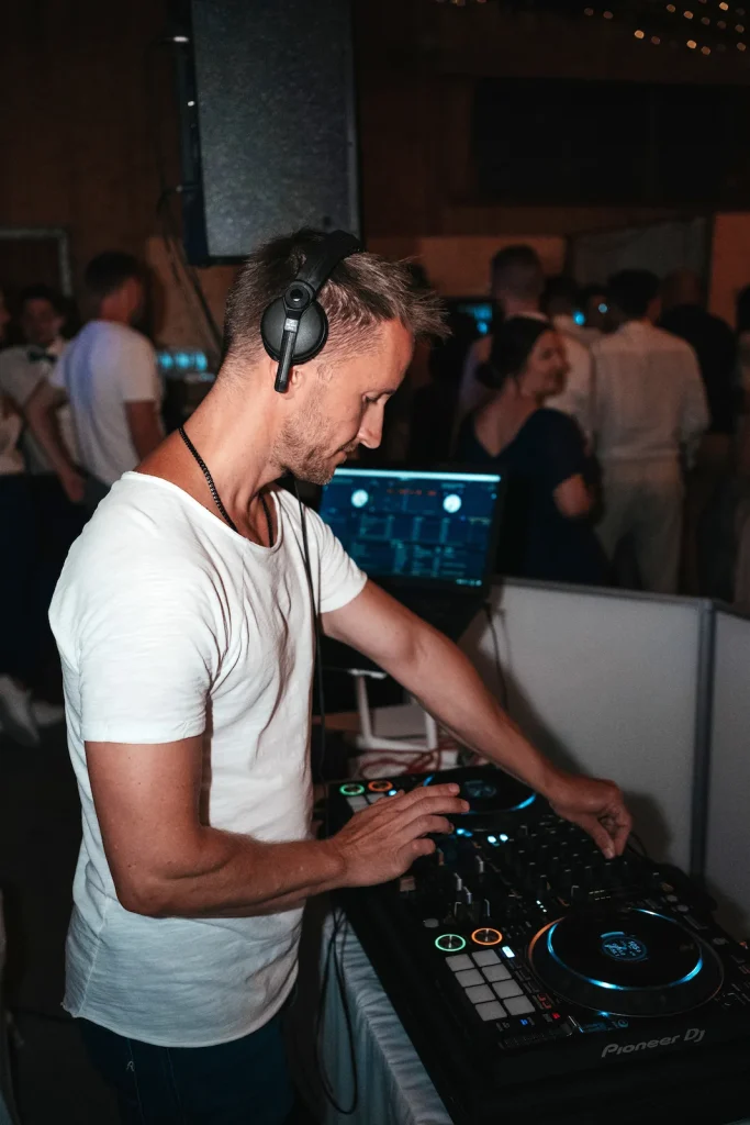 Julian DJ mit Kopfhörern am Mischpult während einer Feier